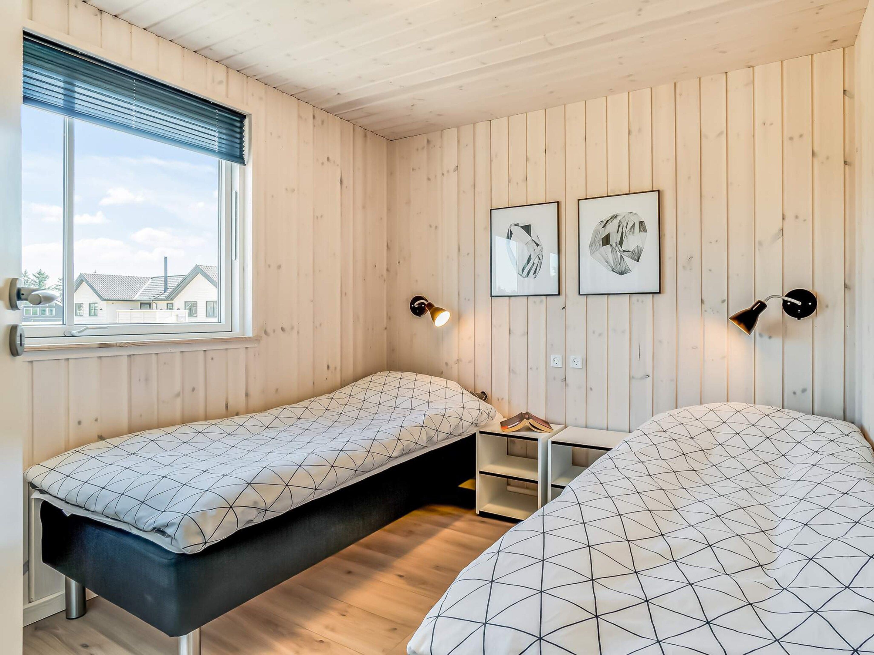A room with two beds, a window, and two wall-mounted lamps.