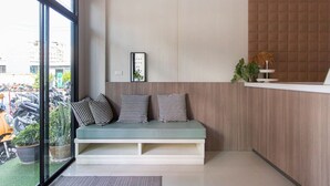 A reception area with a seating area, a framed quote on the wall, and a view of parked motorcycles outside. - Cozy Studio Room Near Beach and Walking Street (Tambon Patong)