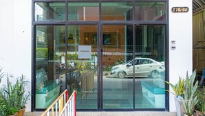 A hotel entrance with a glass facade, a car parked outside, and a sign with the number 179/99. - Cozy Studio Room Near Beach and Walking Street (Tambon Patong)
