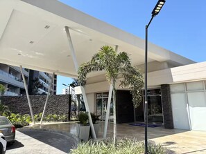 A modern building with a covered entrance, stone facade, and a parking area. - Oceanfront escape, pools, hot tubs & private beach and restaurant. Resort Vibe (Santa Marta)