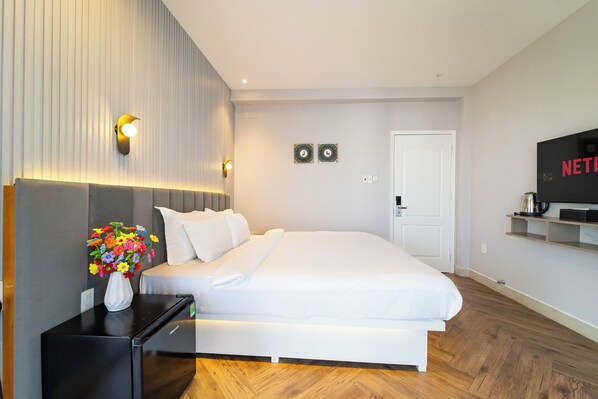 Habitación de hotel moderna con cama, mesita de noche, televisor y paneles decorativos en la pared.
