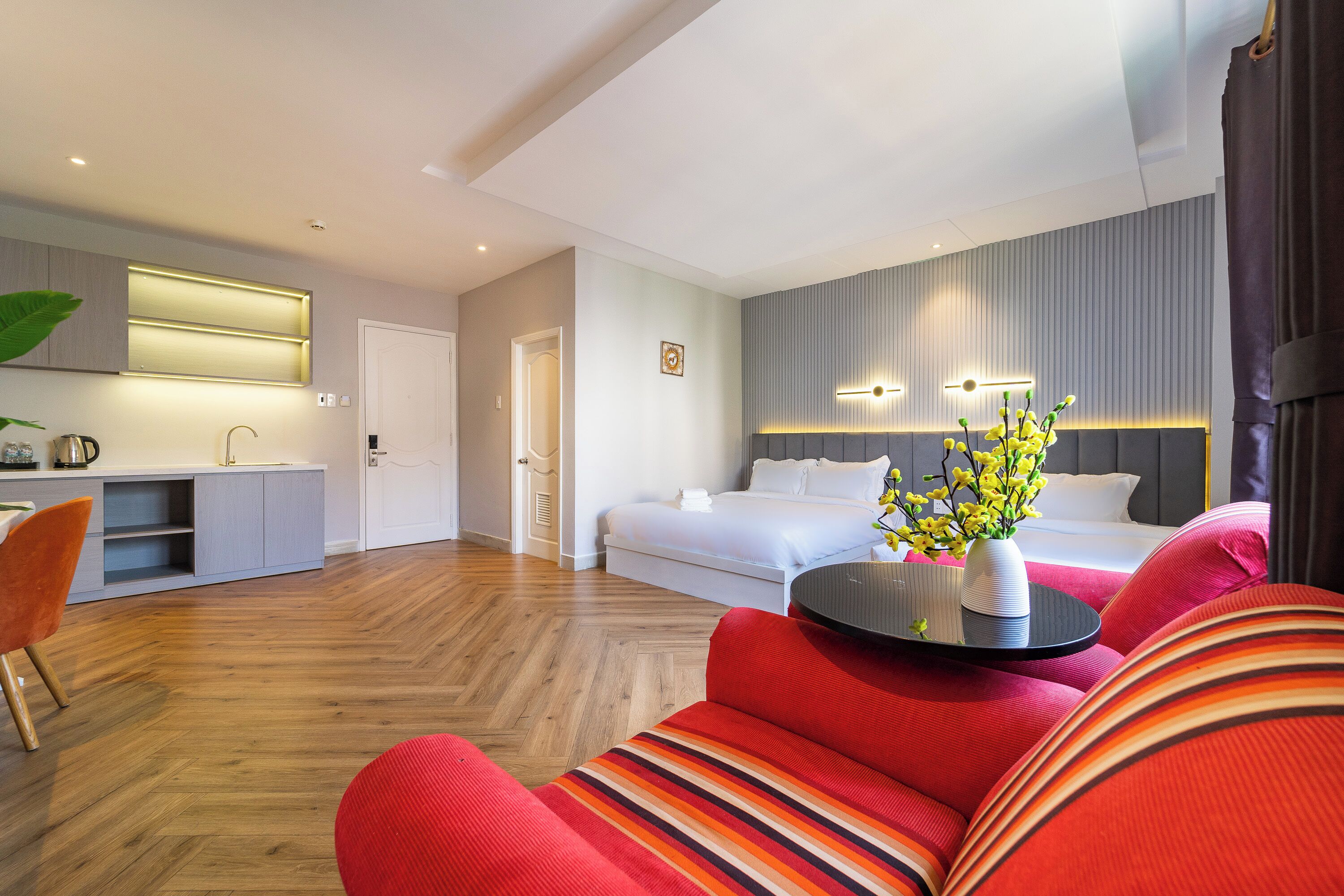 Una habitación de hotel moderna con cama, sofá, zona de comedor y cocina.