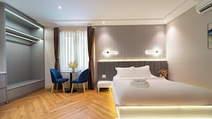 Ein modernes Hotelzimmer mit einem großen Bett, Nachttischen, einem Schreibtisch mit Stühlen und einem fenster mit Vorhängen.