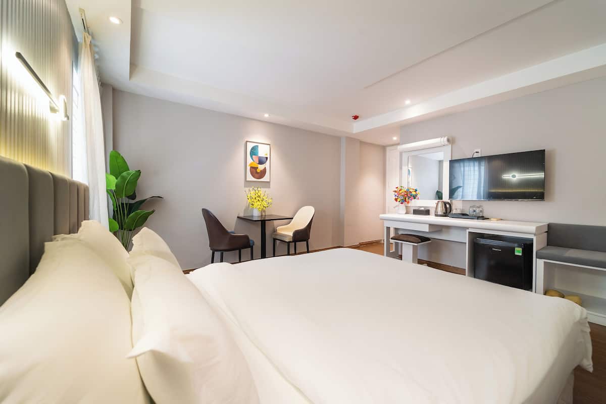 Una habitación de hotel con cama, escritorio, silla y televisión.