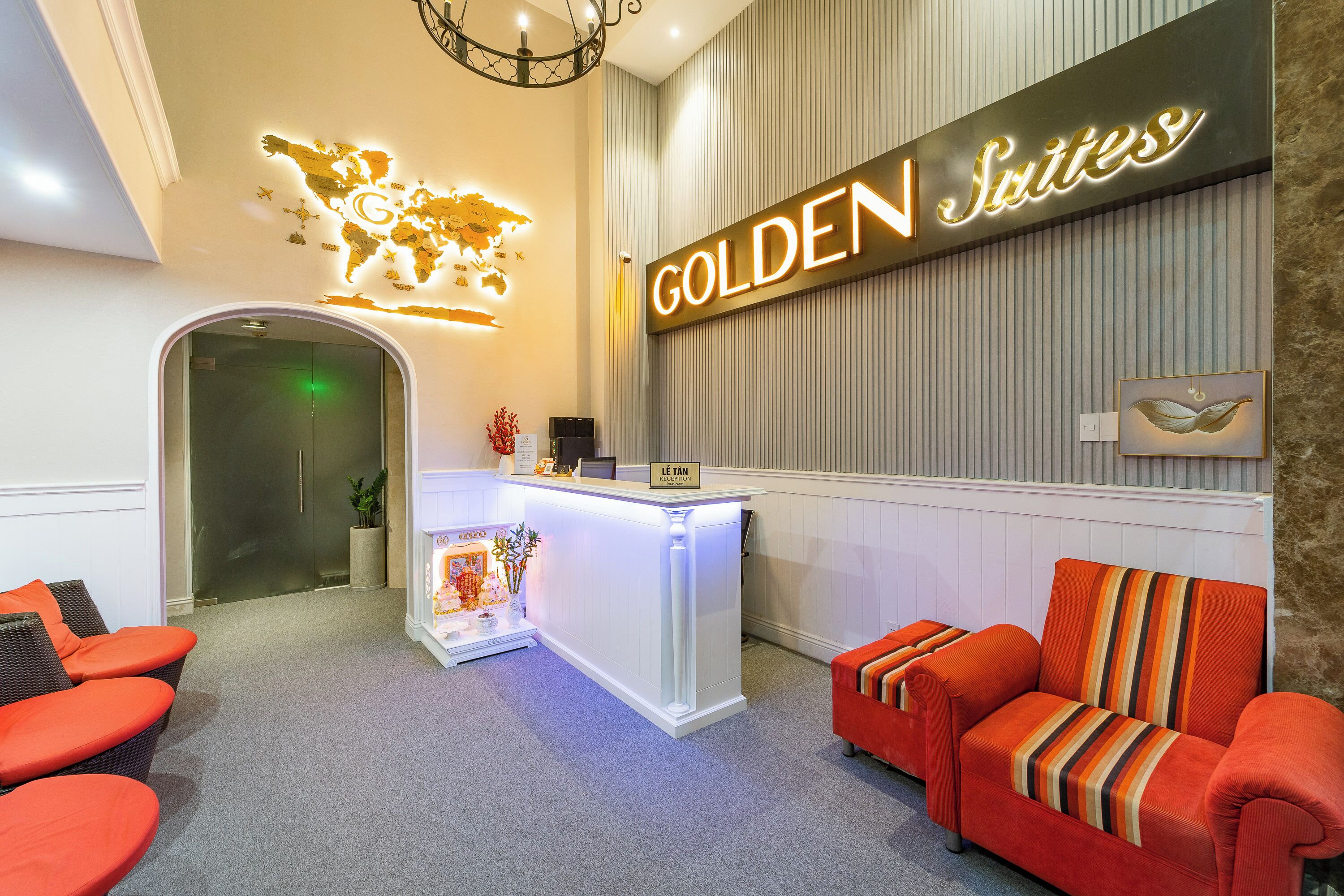 Ein Empfangsbereich mit einem 'GOLDEN Suites' Schild, einem Empfangstisch, einer Weltkarte als Dekoration und einer Rezeption.