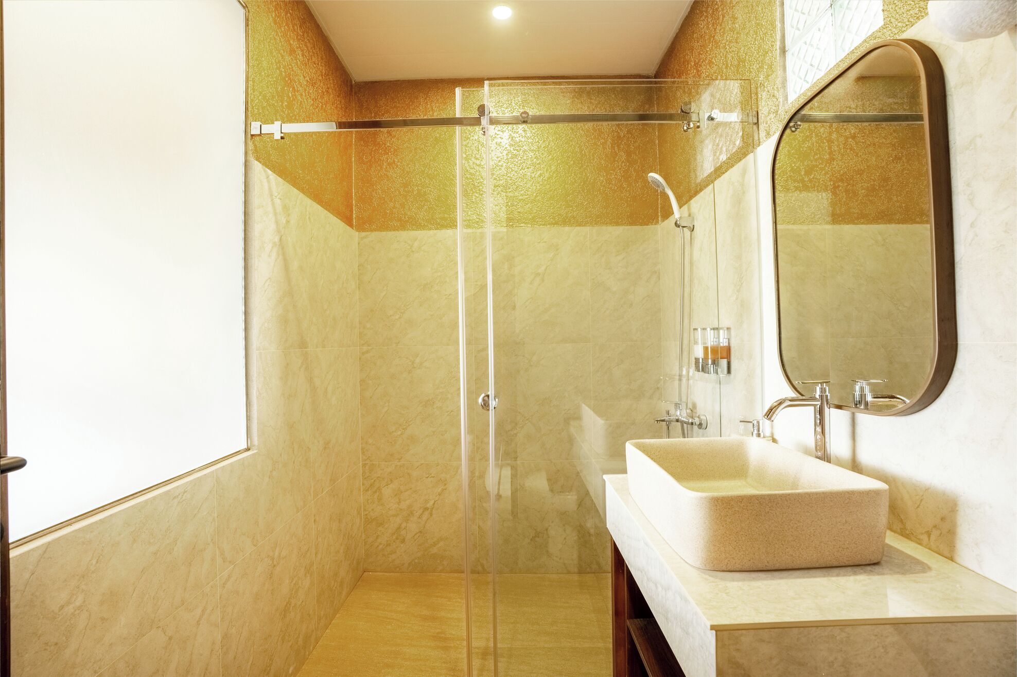 A modern bathroom with a glass-enclosed shower, a large mirror, and a beige sink.