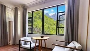 A room with a large window, two chairs, a small round table, and a radiator. - Avatar Peaks Resort (Zhangjiajie)