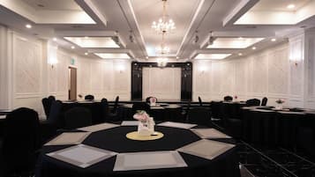 A conference room with a large oval table, multiple chairs, and a chandelier.