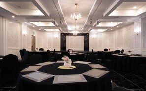 Un salón de conferencias con una gran mesa ovalada, varias sillas y una araña.