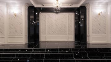 Un lobby amplio con paredes de mármol, un candelabro y una escalera que conduce a un nivel superior.