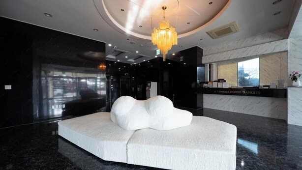 Een moderne lobby met een unieke, witte sculpturale zithoek, een kroonluchter en een receptiebalie.