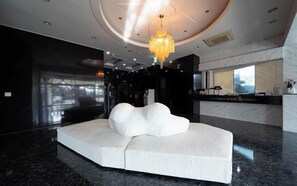 Eine moderne Lobby mit einer einzigartigen, weißen, skulpturalen Sitzgruppe, einer Kristallleuchtre und einer Rezeption.