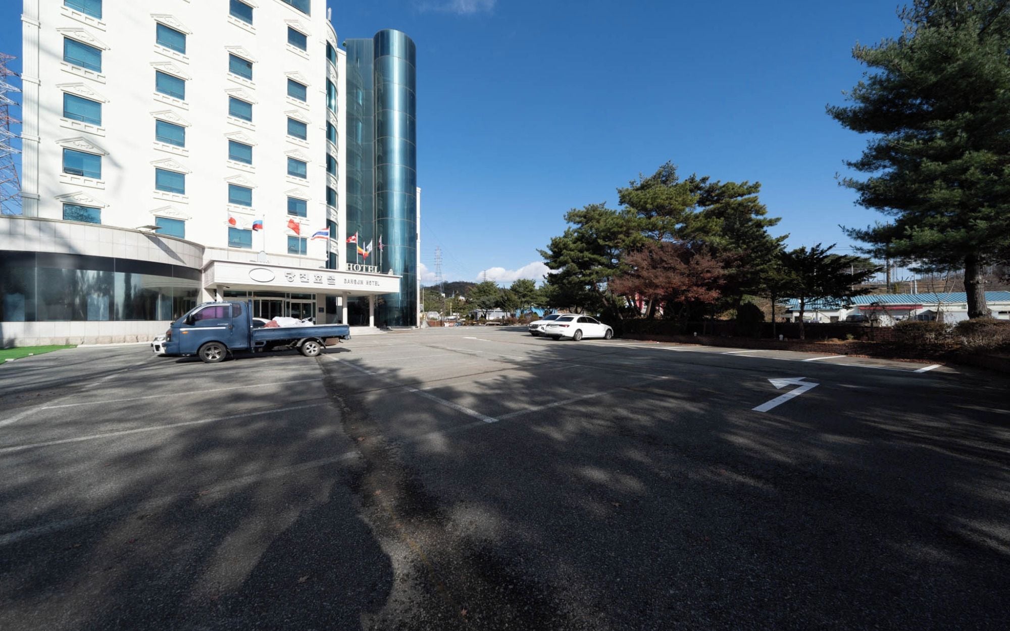 A hotel with a modern facade, a parking lot, and a clear sky.
