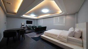 Een moderne hotelkamer met een bed, een bureau en een zithoek.