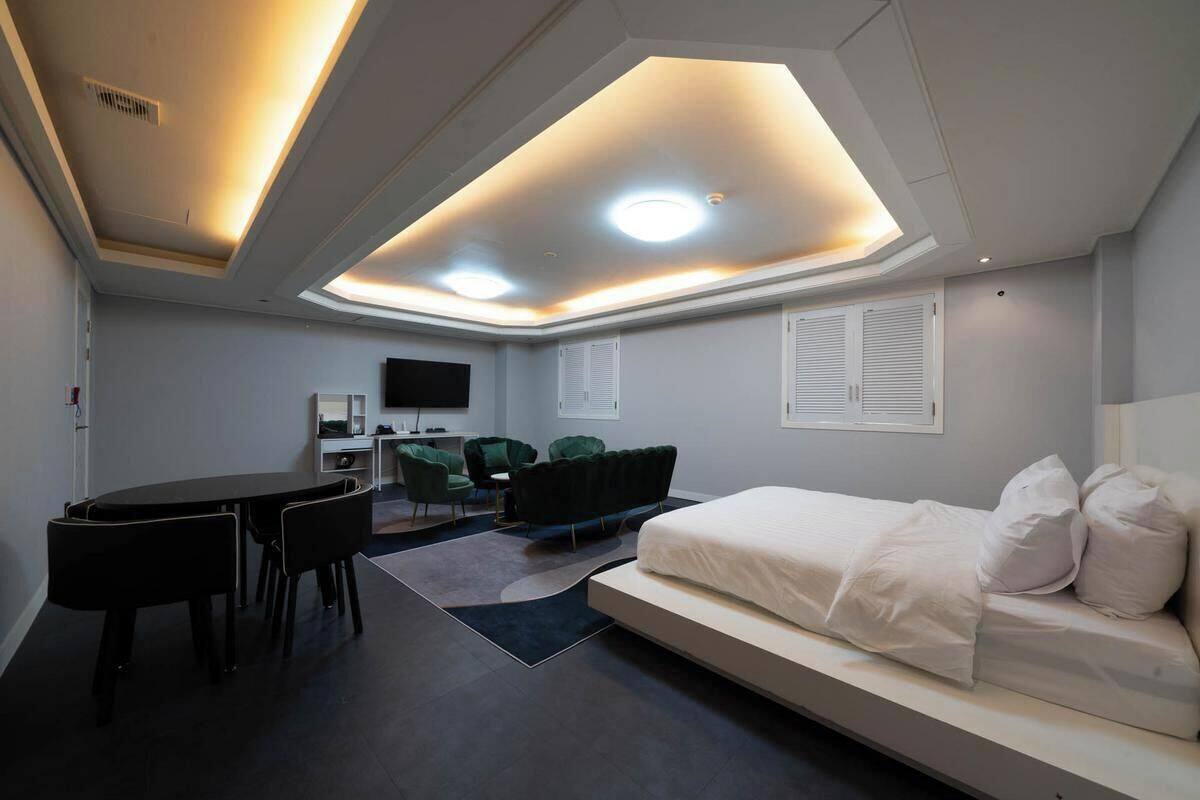 A modern hotel room with a bed, a desk, and a seating area.