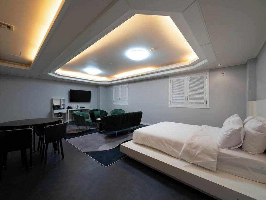 A modern hotel room with a bed, a desk, and a seating area.