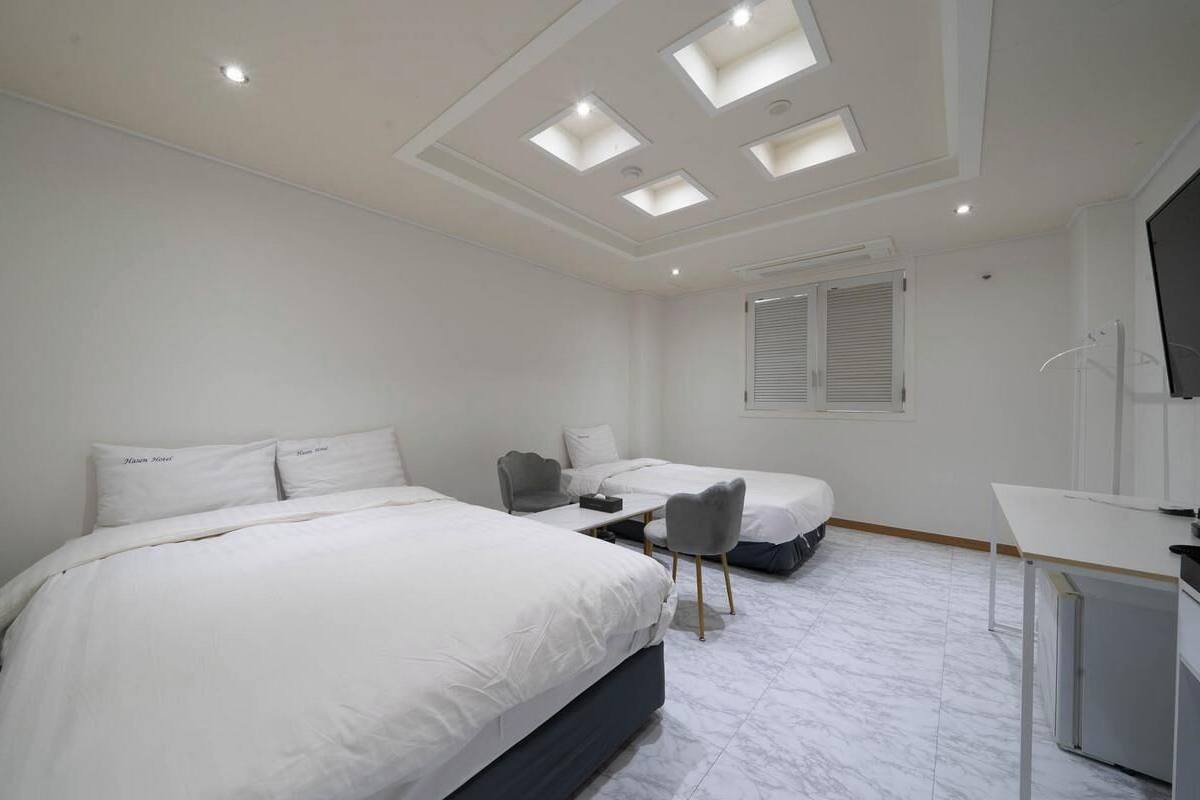 A hotel room with two beds, a desk, and a TV.