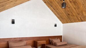 A bedroom with two beds, wooden ceiling, white walls, and a sloped roof. - Sanctuary House (Dieng Kulon)