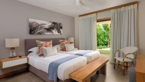 Ein Schlafzimmer mit zwei Betten, einem Deckenventilator, einem Nachttisch mit Lampe, einer Bank und einem Stuhl.