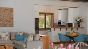 Ein modernes Wohnzimmer mit Sofa, Esstisch und Stühlen. Es gibt eine Küchenzeile mit Schränken und einem Fenster.