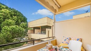 A balcony with a table set for breakfast, a chair, and a view of a building and trees. - Casetta Azzurra Flat With Parking in Capalbio (Capalbio)