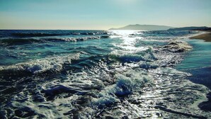 A beach with waves, a clear sky, and distant mountains. - Casetta Azzurra Flat With Parking in Capalbio (Capalbio)