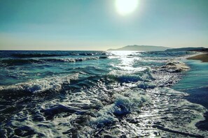 A beach with waves, a clear sky, and distant mountains. - Casetta Azzurra Flat With Parking in Capalbio (Capalbio)