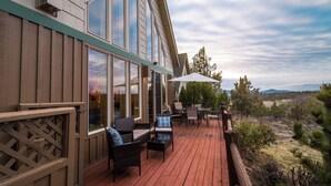 A deck with outdoor furniture, large windows, and a view of the surrounding landscape.