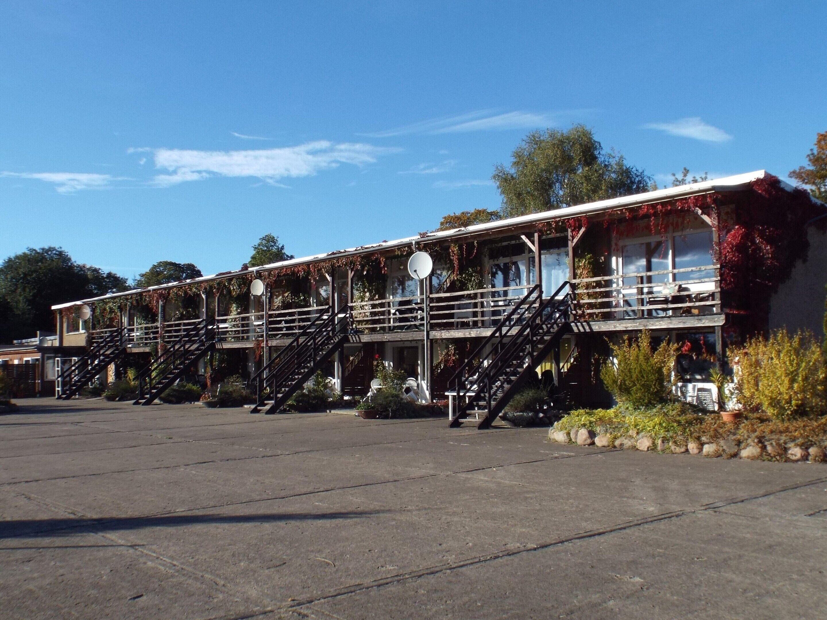 A multi-story building with external staircases, a flat roof, and a parking lot.