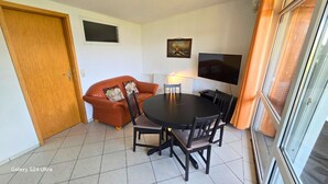 Comedor con una mesa redonda y sillas, un sofá, un televisor y una puerta.