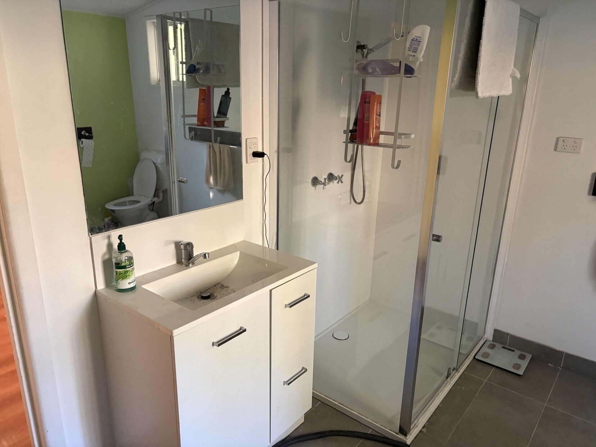 A bathroom with a white sink, mirror, and glass shower enclosure.