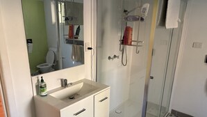 Un baño con lavabo blanco, espejo y cabina de ducha de vidrio.