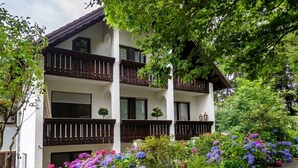 A multi-story building with balconies, surrounded by lush greenery and vibrant flowers. - Belvilla Heiderhof 1-bedroom Apartment (Obersteinebach)
