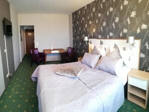 A hotel room with a bed, a desk, two chairs, a TV, and a nightstand. - Belvilla Heiderhof 1-bedroom Apartment (Obersteinebach)