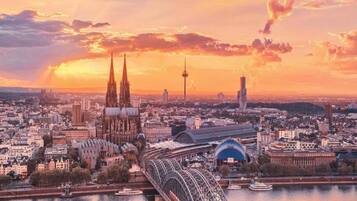 Stadtansicht mit einem markanten Dom, einer Brücke und einem Turm vor einem Sonnenuntergangshimmel.