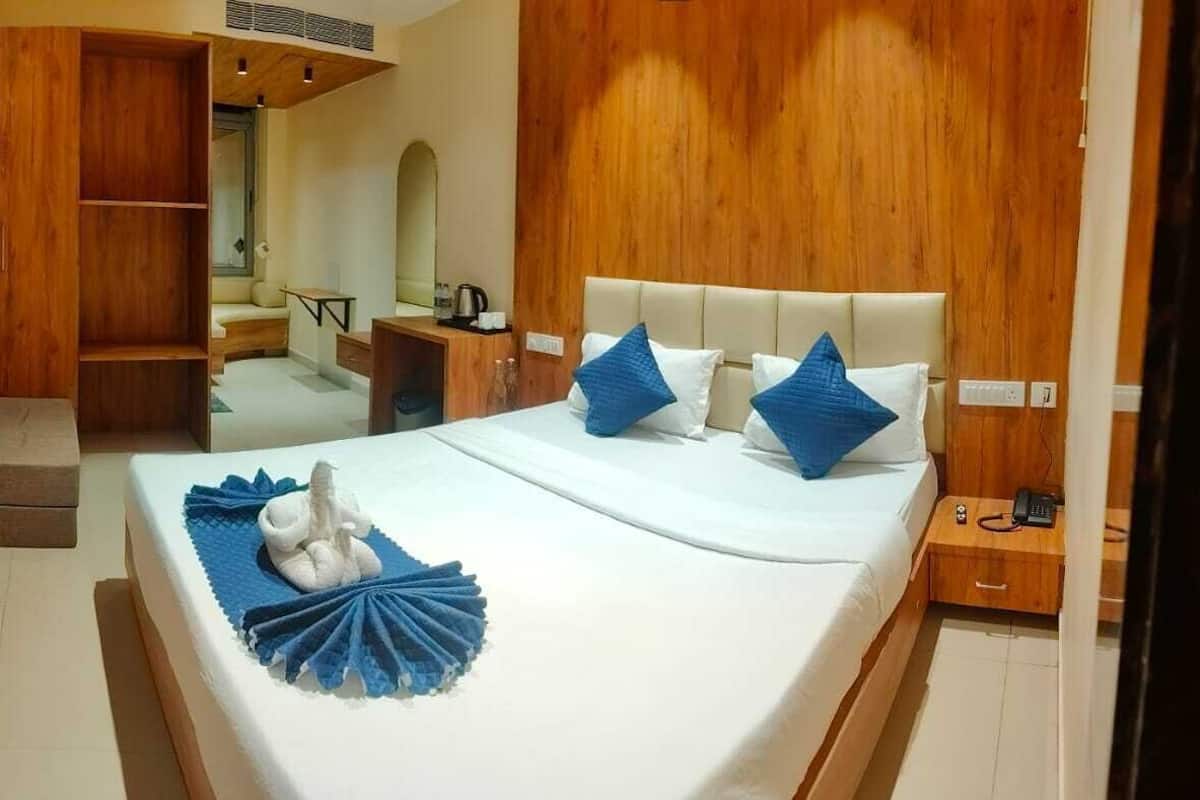 A hotel room with a bed, a desk, a chair, a wardrobe, and a television.