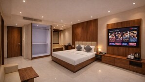 A modern hotel room with a large bed, a TV mounted on the wall, a wardrobe, and a seating area. - Hotel Regal Crest (Bhubaneshwar)