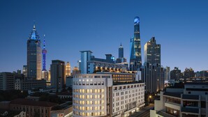 A cityscape at dusk with modern buildings, including a prominent skyscraper with a unique design. - Atour Hotel Shanghai Yuyuan Yaduo  Bund (Shanghai)