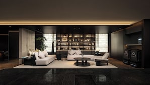 A modern living room with a sofa, armchairs, a coffee table, and a bookshelf filled with books and decorative items. - Atour Hotel Shanghai Yuyuan Yaduo  Bund (Shanghai)