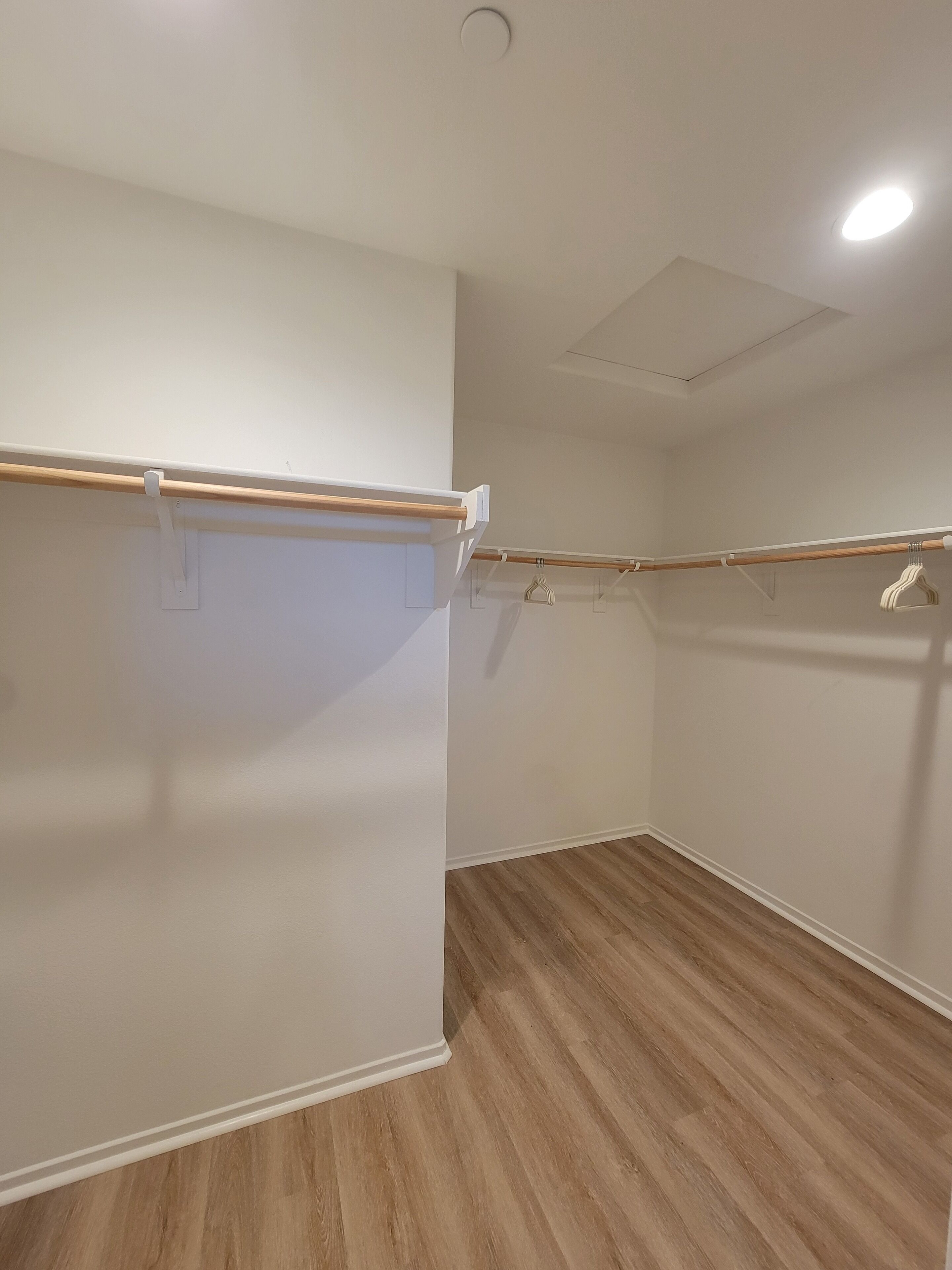 A room with a wooden floor, white walls, and a ceiling with a recessed light fixture.