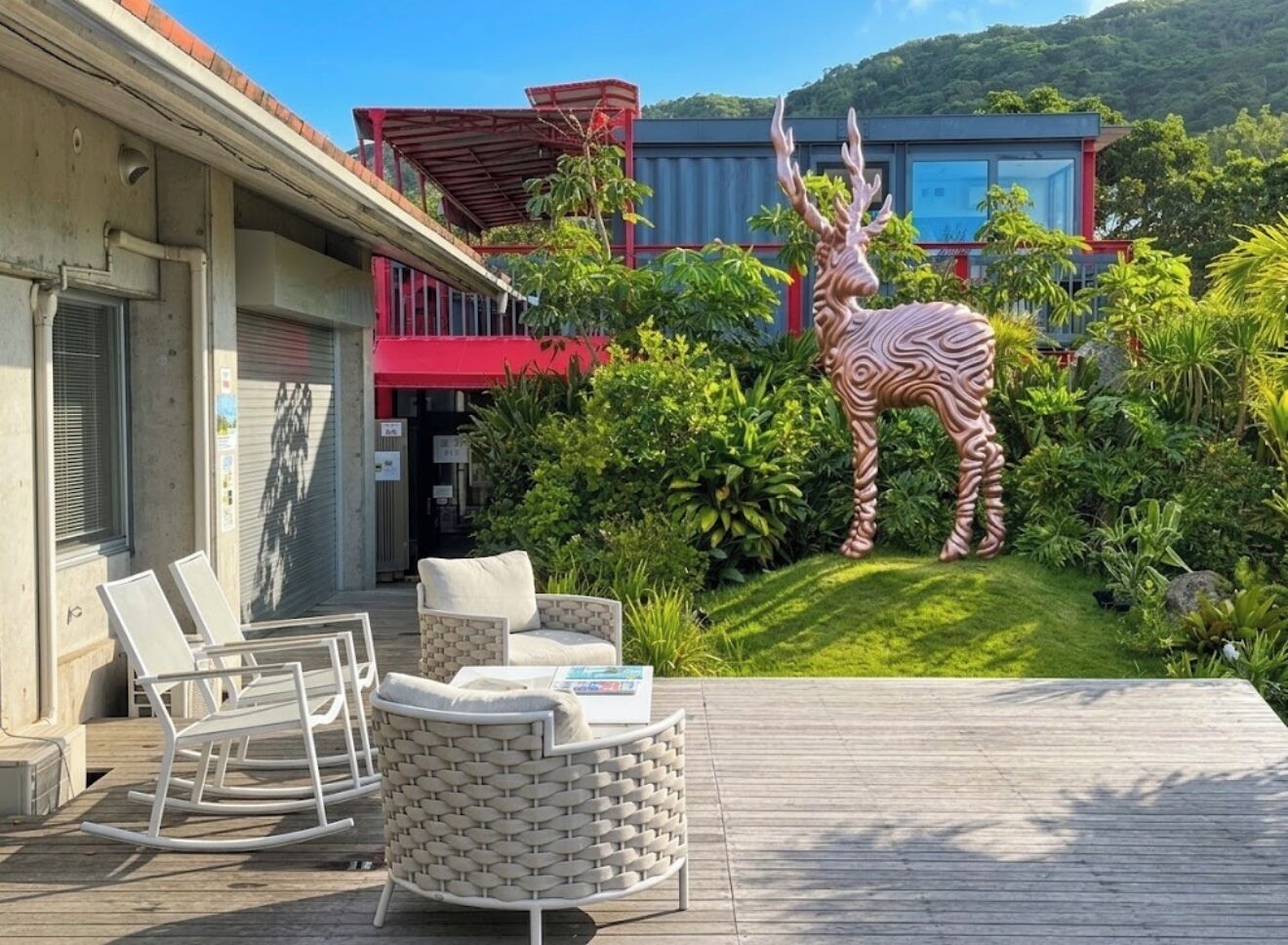 Une terrasse avec des meubles d’extérieur, une statue de zèbre et un bâtiment à la façade rouge et bleue.
