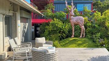 Une terrasse avec des meubles d’extérieur, une statue de zèbre et un bâtiment à la façade rouge et bleue.