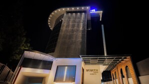 A modern hotel entrance with a curved facade, a prominent staircase, and a sign for 'Ananta Express Grand Tower.' - Ananta Express (Katra)