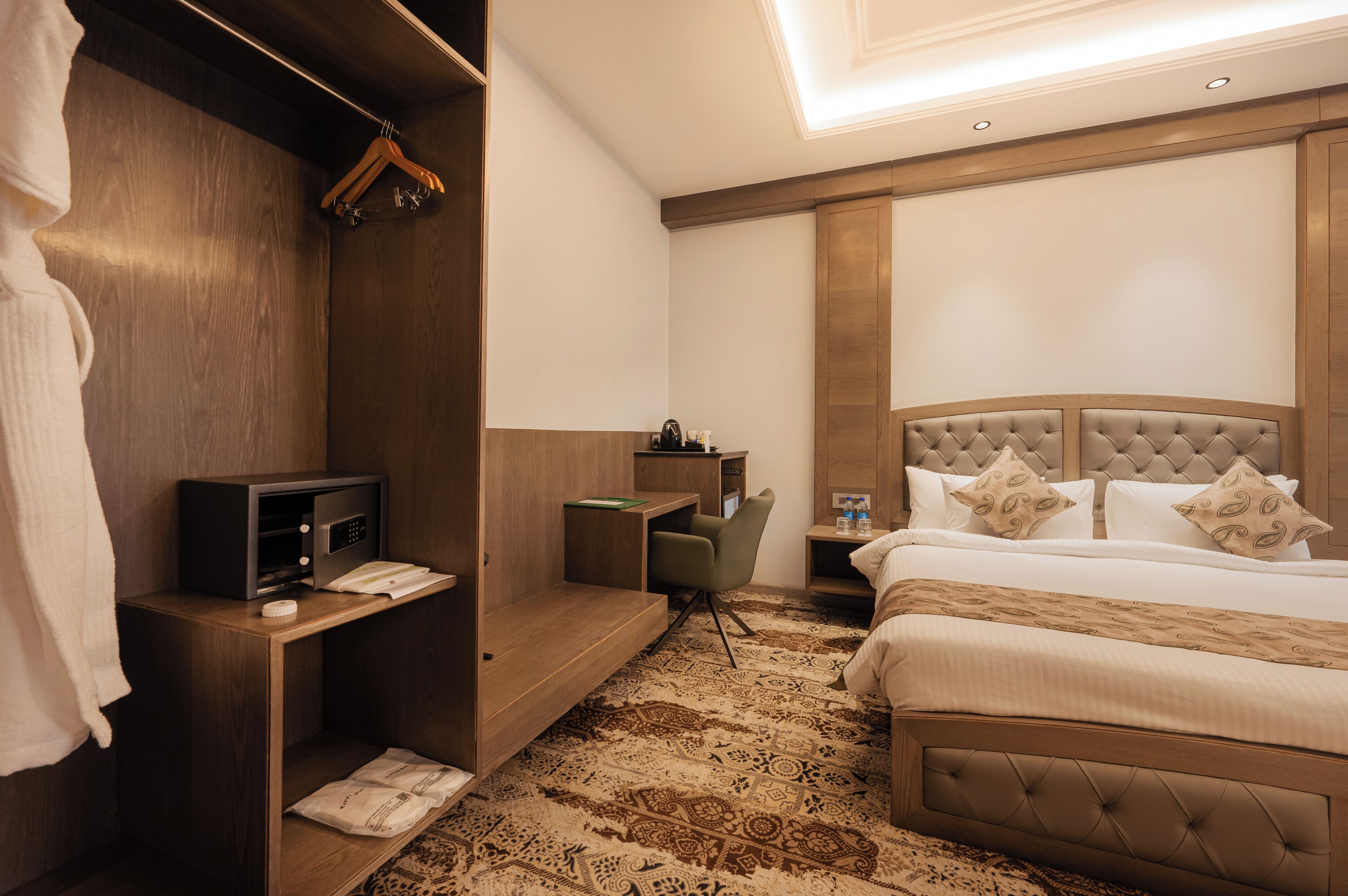 A hotel room with a bed, a desk, a chair, a microwave, and a wardrobe.