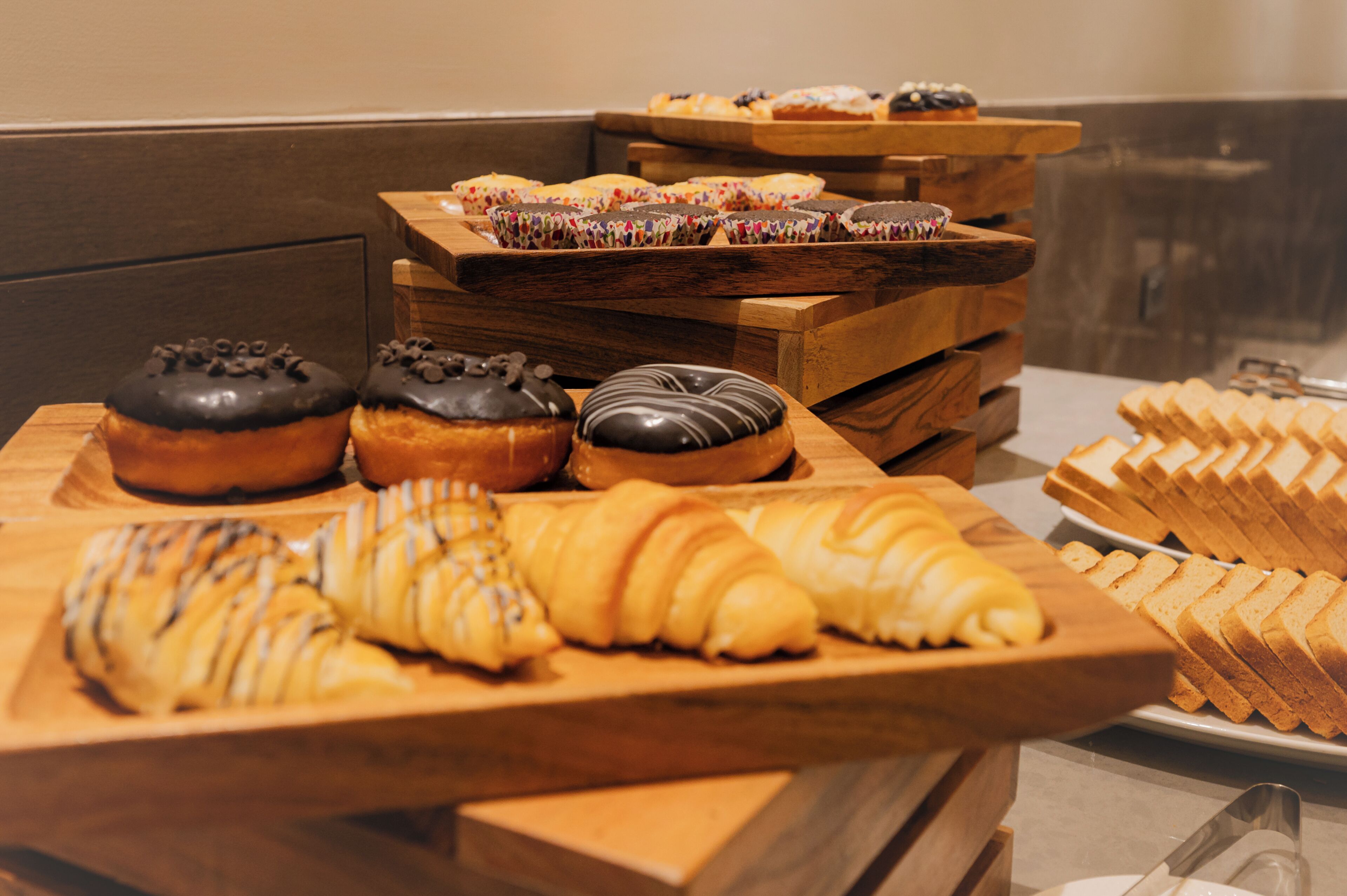 Diversa variedad de pasteles y panes expuestos sobre tablas de madera en una panadería.