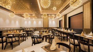 A spacious dining area with multiple tables, elegant chandeliers, and a modern ceiling design. - Ananta Express (Katra)