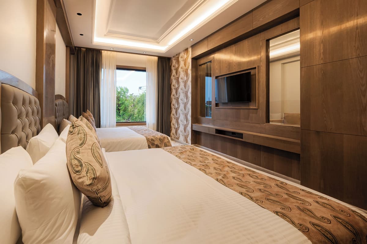 A hotel room with two beds, a TV, and a large window.