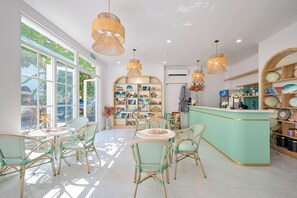 A cafe with wicker chairs, a central round table, and a display of decorative plates. - Casa Del Mar Boutique Hotel (Phu Quoc)
