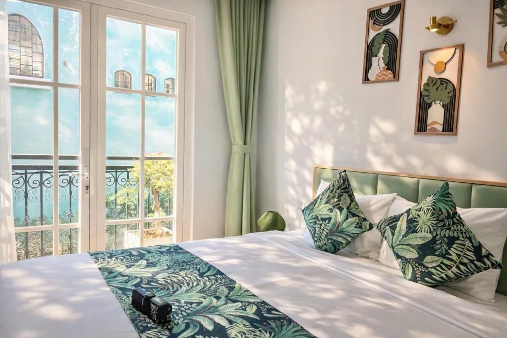 A bedroom with a large bed, a view of a balcony, and artwork on the wall.