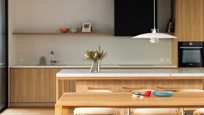 Una cucina moderna con mobili in legno, un'isola centrale e una lampada a sospensione.